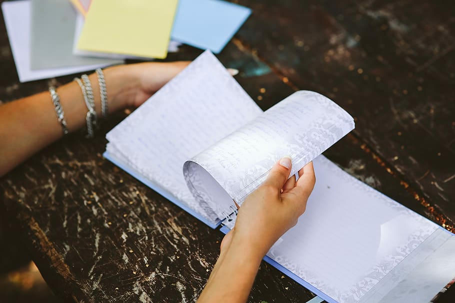 Woman reading a diary by the table, book, notebook, hands, memories