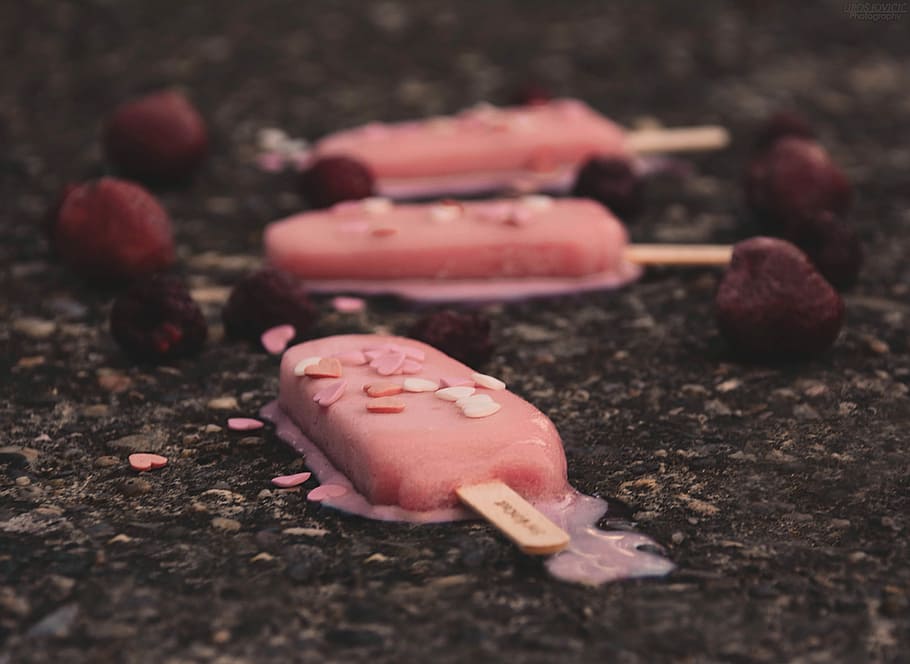 three pink ice creams, tilt photography of melted ice cream sticks