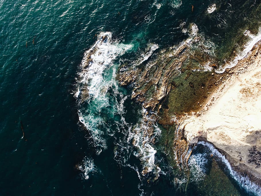 aerial photography of brown rocky shoreline at daytime, brown sand beside body of water during daytme HD wallpaper