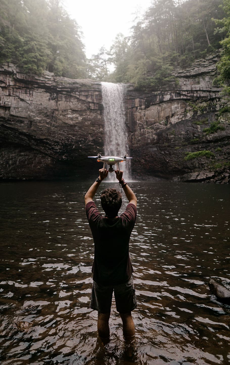 man holding drone facing waterfalls, man using his white drone HD wallpaper