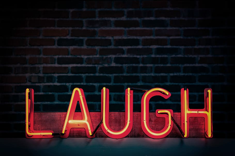 Laugh neon signage, red laugh neon light sign against black brick background