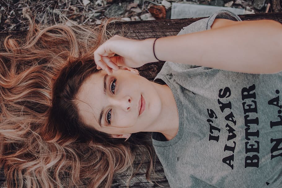 woman wearing gray t-shirt lying on ground, woman lying on brown rag while holding her face HD wallpaper