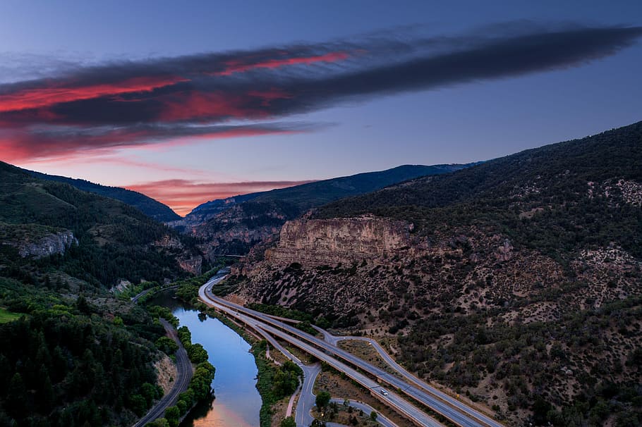 aerial photography of concrete road near river and mountain during sunset, aerial photography of road between mountains HD wallpaper