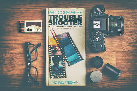 Photographers Trouble Shooter book between DSLR camera, Marlboro match box and eyeglasses, Photographers Trouble Shooter by Michael Freeman book HD wallpaper