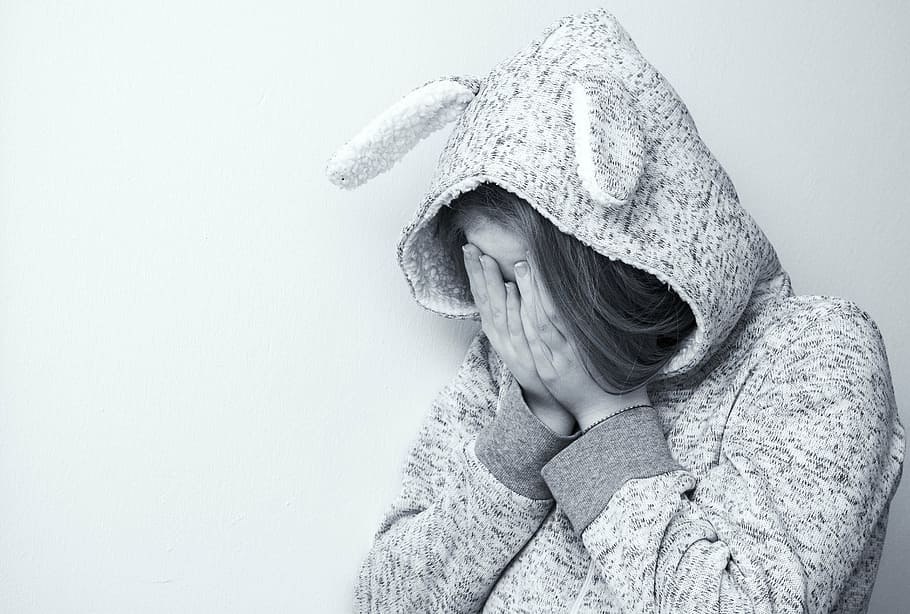 greyscale photo of woman wearing hoodie crying, desperate, sad
