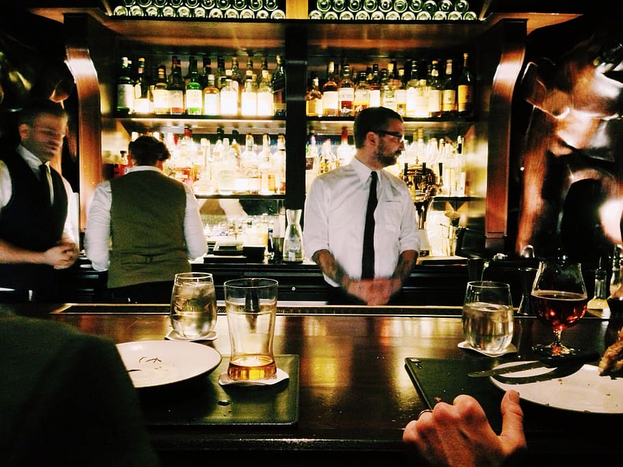 bartender standing beside table, men's white long-sleeved shirt