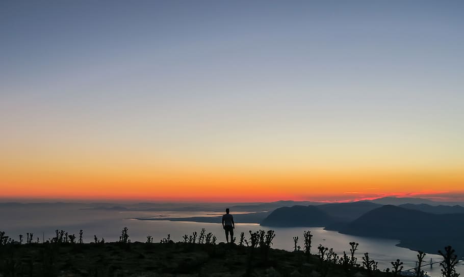 silhouette photo of man standing on mountain, silhouette of man standing on cliff looking coastlines landscape photography HD wallpaper
