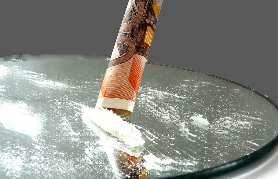 closeup photography of rolled banknote with cocaine, addiction