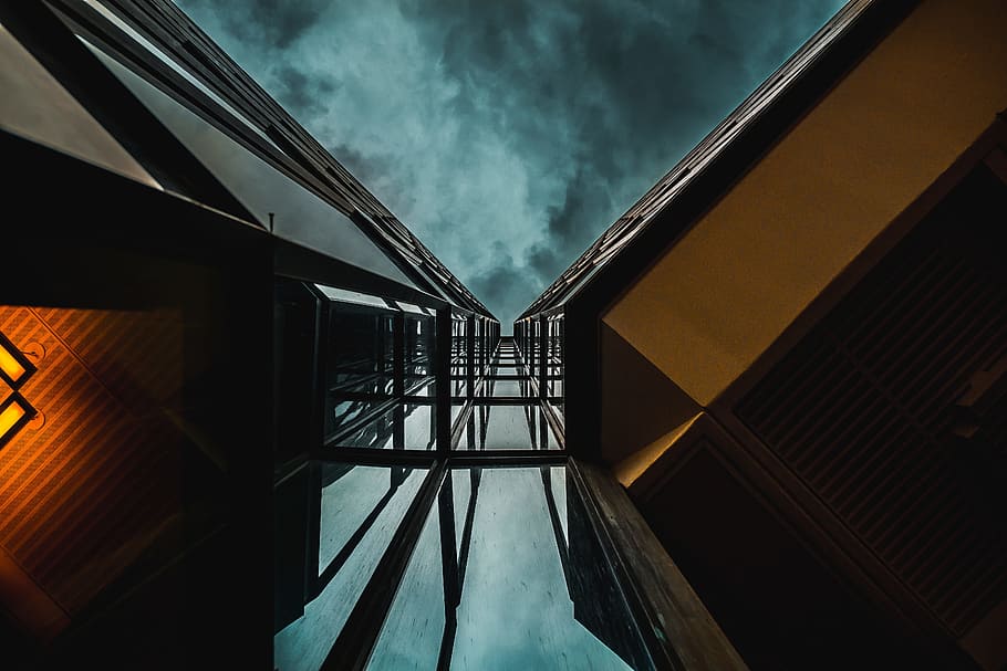 low angle photography of high-rise building under blue clouds, eye's worm view of high-rise building under dark sky