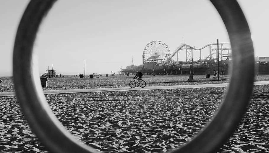 grayscale photography of person riding bike, person riding bicycle from afar looking through ring in grayscale photography