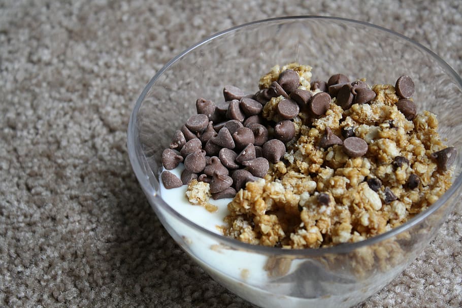 chocolate and cereal with milk served on clear glass bowl, granola