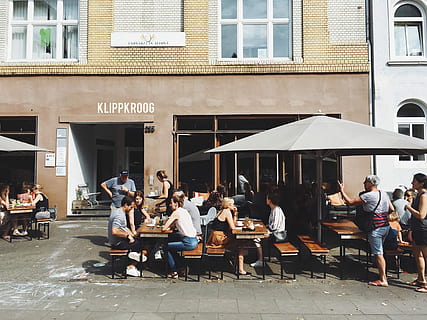 group of people sitting on benches with tables beside Klippkroog store front at daytime, group of people sit on patio set HD wallpaper