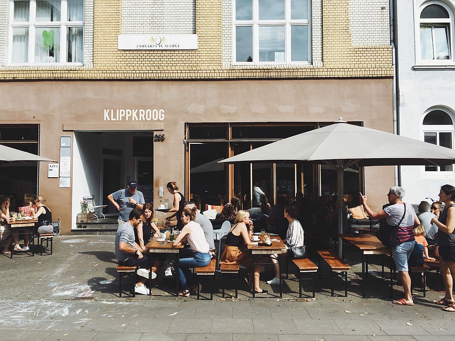 group of people sitting on benches with tables beside Klippkroog store front at daytime, group of people sit on patio set HD wallpaper