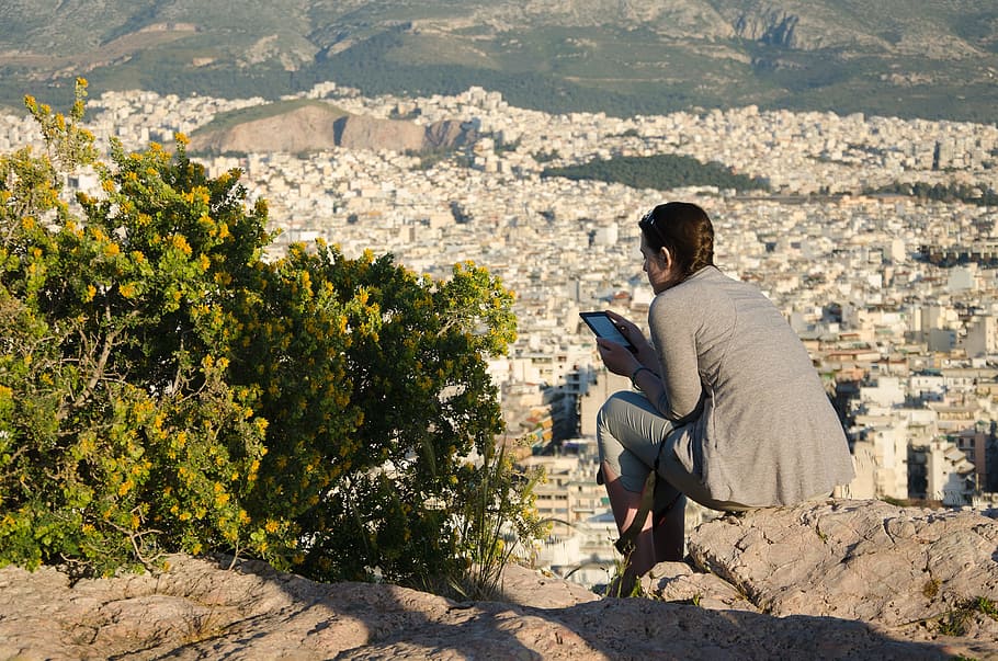 woman sitting on cliff holding smartphone, Greece, Athens, Areopagus HD wallpaper