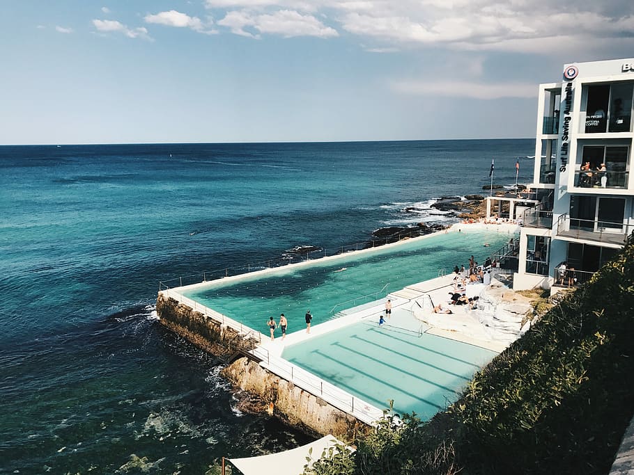large swimming pool near ocean in landscape photography, person standing near swimming pool HD wallpaper