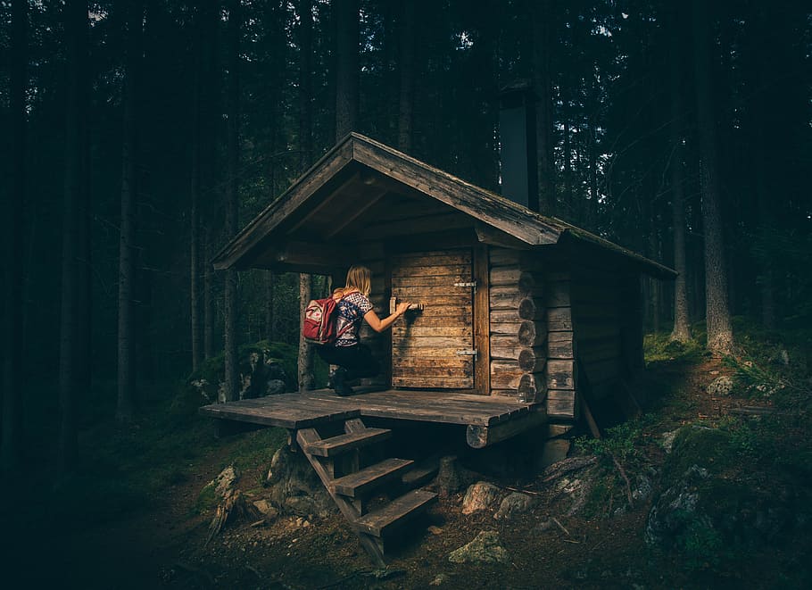 girl knocking on wooden door, woman in grey shirt with red backpack about to enter a small brown house surrounded with trees HD wallpaper