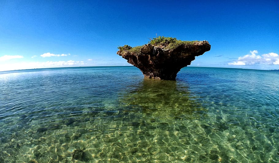 brown stone formation in the middle of body of water, photo, small island