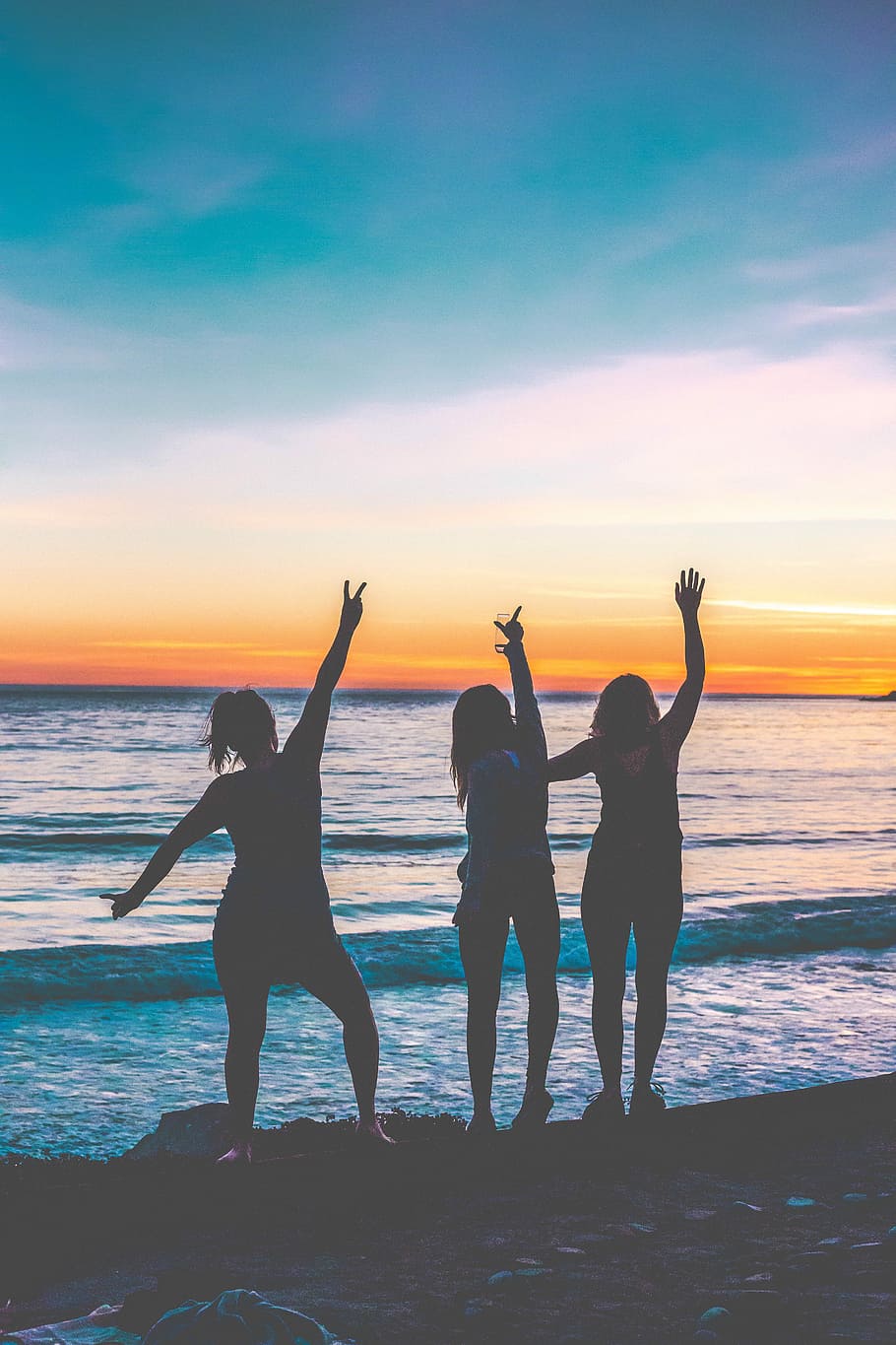 silhouette photo of three women standing near shoreline, three women standing in front of sea while raising hands HD wallpaper