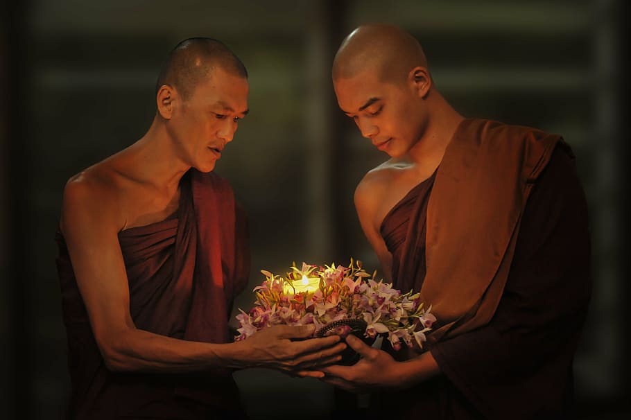 two monks carrying flowers with candle, theravada buddhism, passing candle