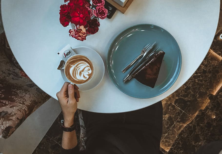 person holding white ceramic mug, person holding a cup of coffee with sliced cake on side HD wallpaper