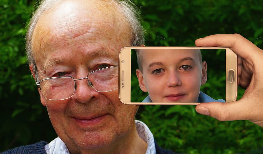 person holding turned on smartphone near man's face, youth, age