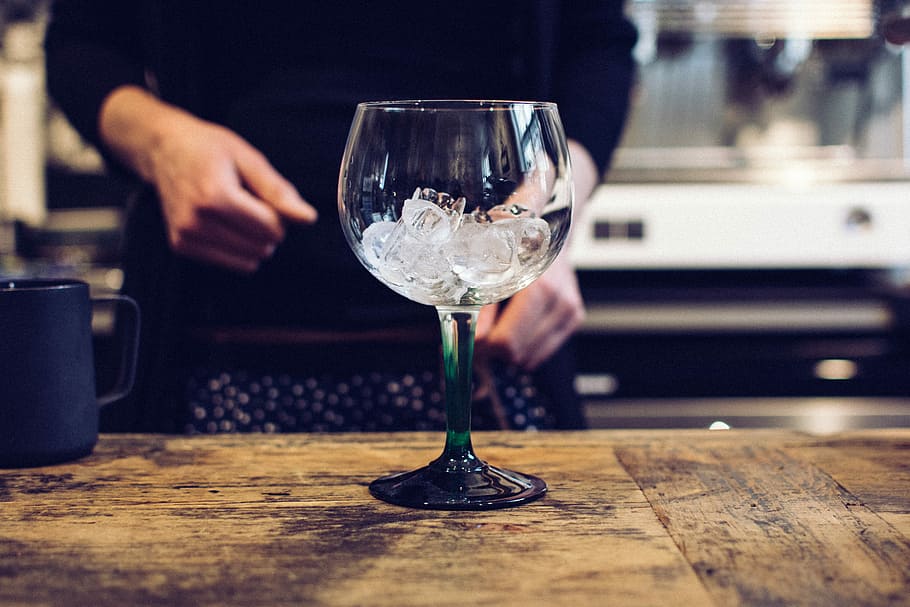 Empty glass with ice, drink, hands, alcohol, wineglass, table