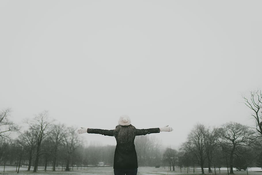 woman in black long-sleeved shirt standing and facing trees with stretched arms under white sky, woman wearing black jacket and white hat standing near road during noontime, HD wallpaper