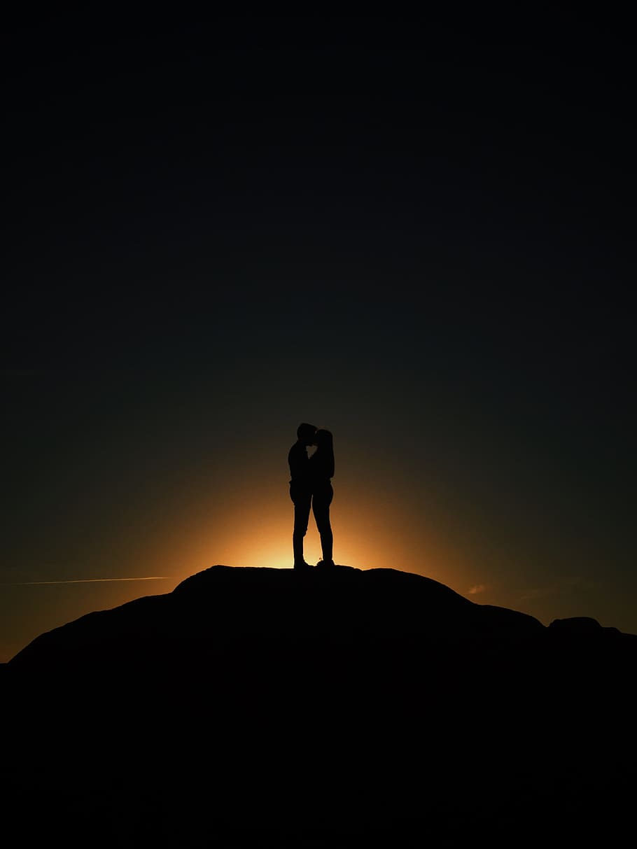 man and woman kissing, silhouette of couple in the mountain, golden hour