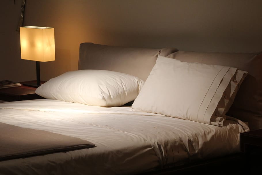 empty bed with white comforter set beside turned on table lamp HD wallpaper