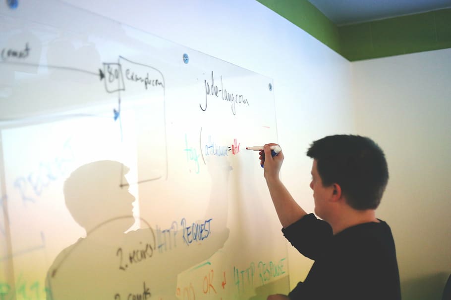 man in black shirt writing on whiteboard inside room, person HD wallpaper