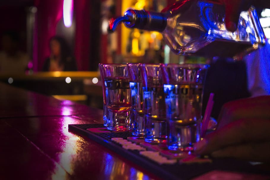 person pouring liquor on glasses, tequila, bar, cups, bar - drink establishment