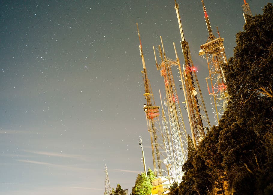 brown truss towers during daytime, assorted towers near a cliff during night time HD wallpaper