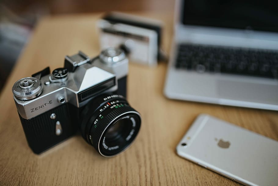 Old Zenit camera and a Canon camera with black-and-white photos on a wooden table HD wallpaper