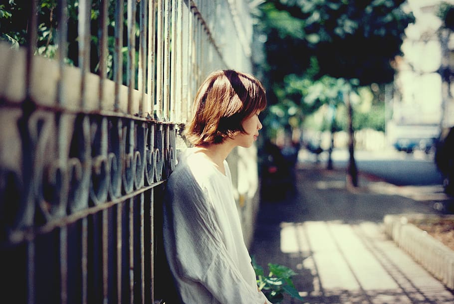 woman lying on black steel wall, woman in white shirt leaning on brown metal gate at daytime, HD wallpaper