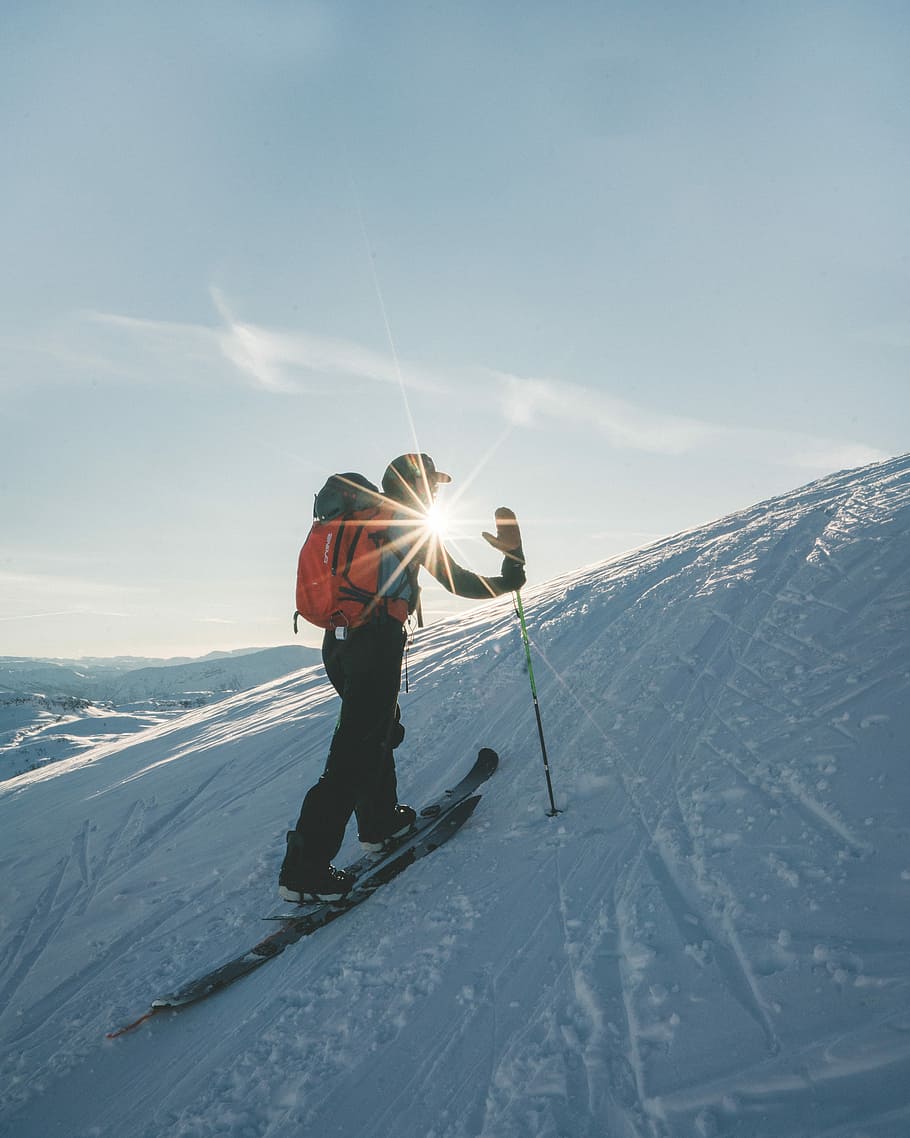 Splitboard hike, man wearing skis walking up snow covered hill during day HD wallpaper