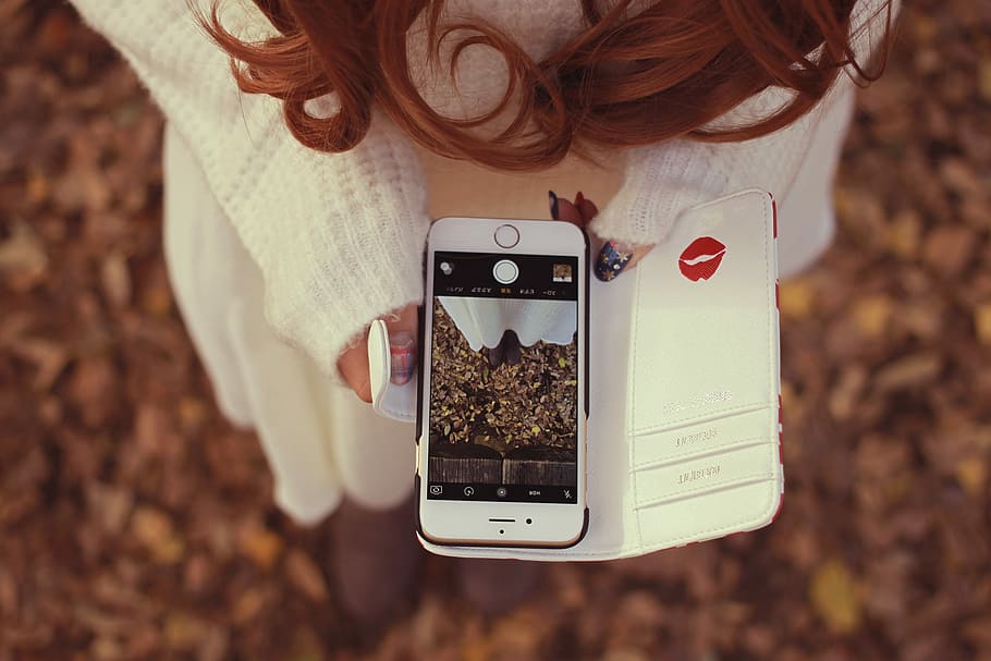 shallow focus photography of woman in white sweater holding gold iPhone 6 showing camera interface HD wallpaper
