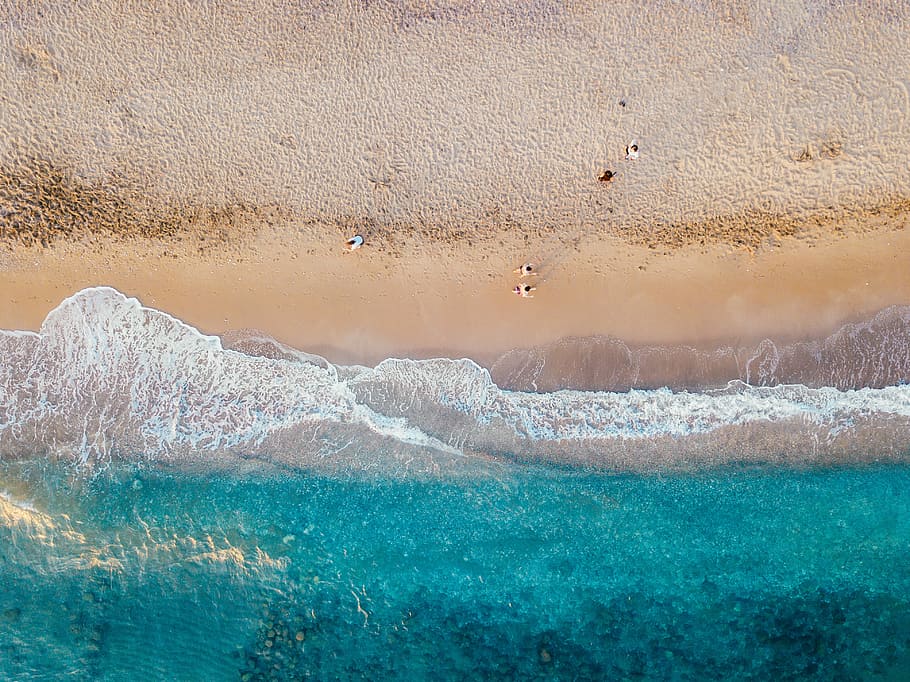 aerial photo of people standing on sand beach near teal sea wave at daytime, aerial photo of people walking on beach during daytime