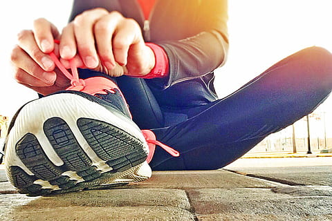 woman tying her shoe lace sitting on the gray concrete pavement HD wallpaper