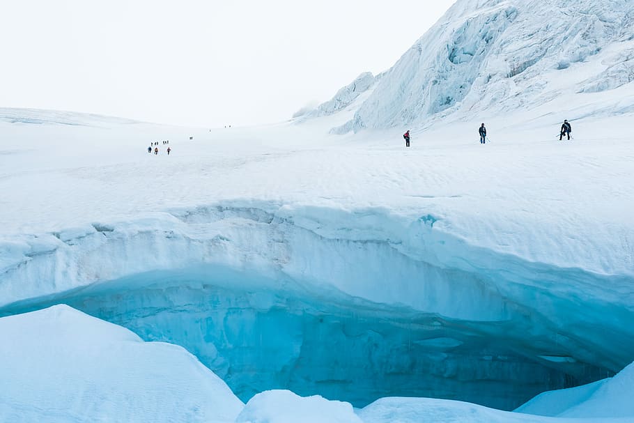 mountain covered by snow, people standing on ice field near cliff HD wallpaper