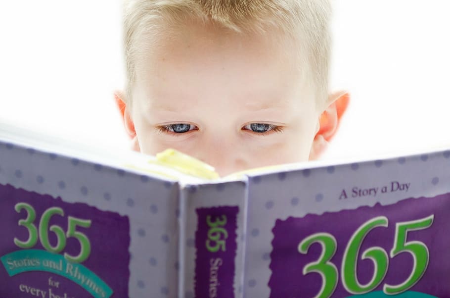 boy holding a 365 story book, learning, development, looking