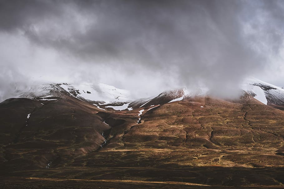 landscape photo of mountain covered by clouds, photo of brown mountain with snow on top under cloudy sky HD wallpaper