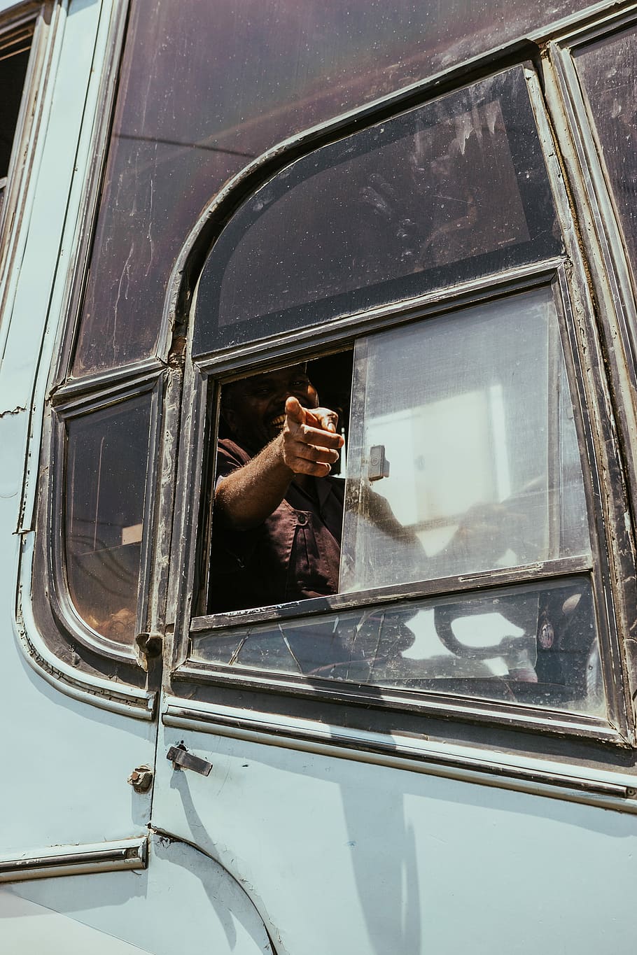 man riding bus, person inside gray vehicle, window, pointing HD wallpaper