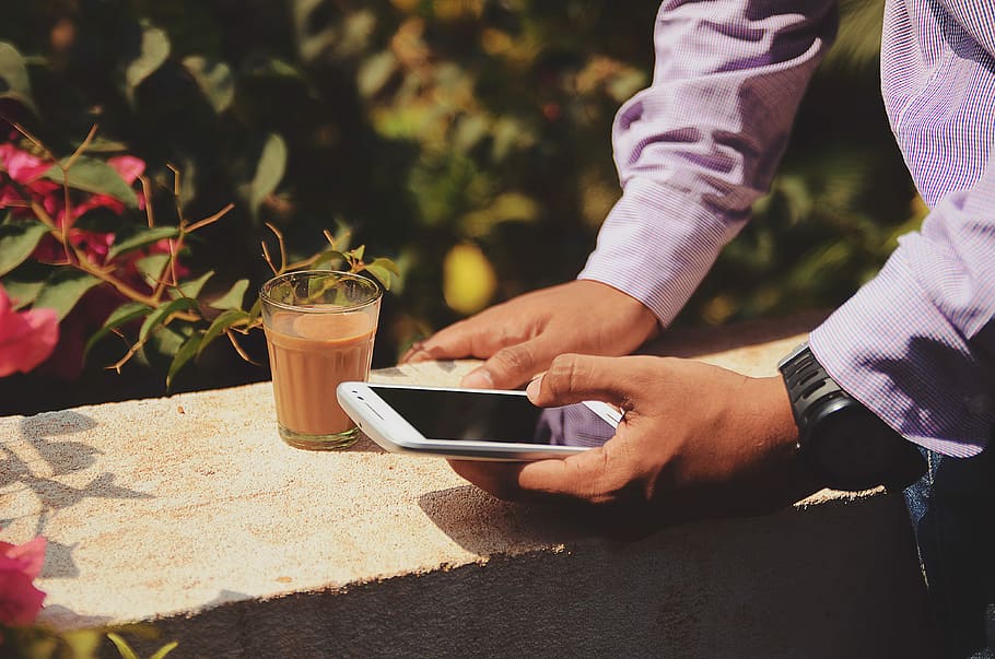 man using smartphone beside drinking glass, person in purple dress shirt holding smartphone near clear drinking glass HD wallpaper