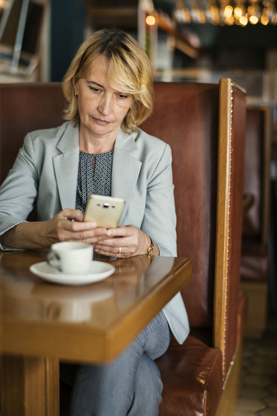 woman holding smartphone while sitting on chair near table, american
