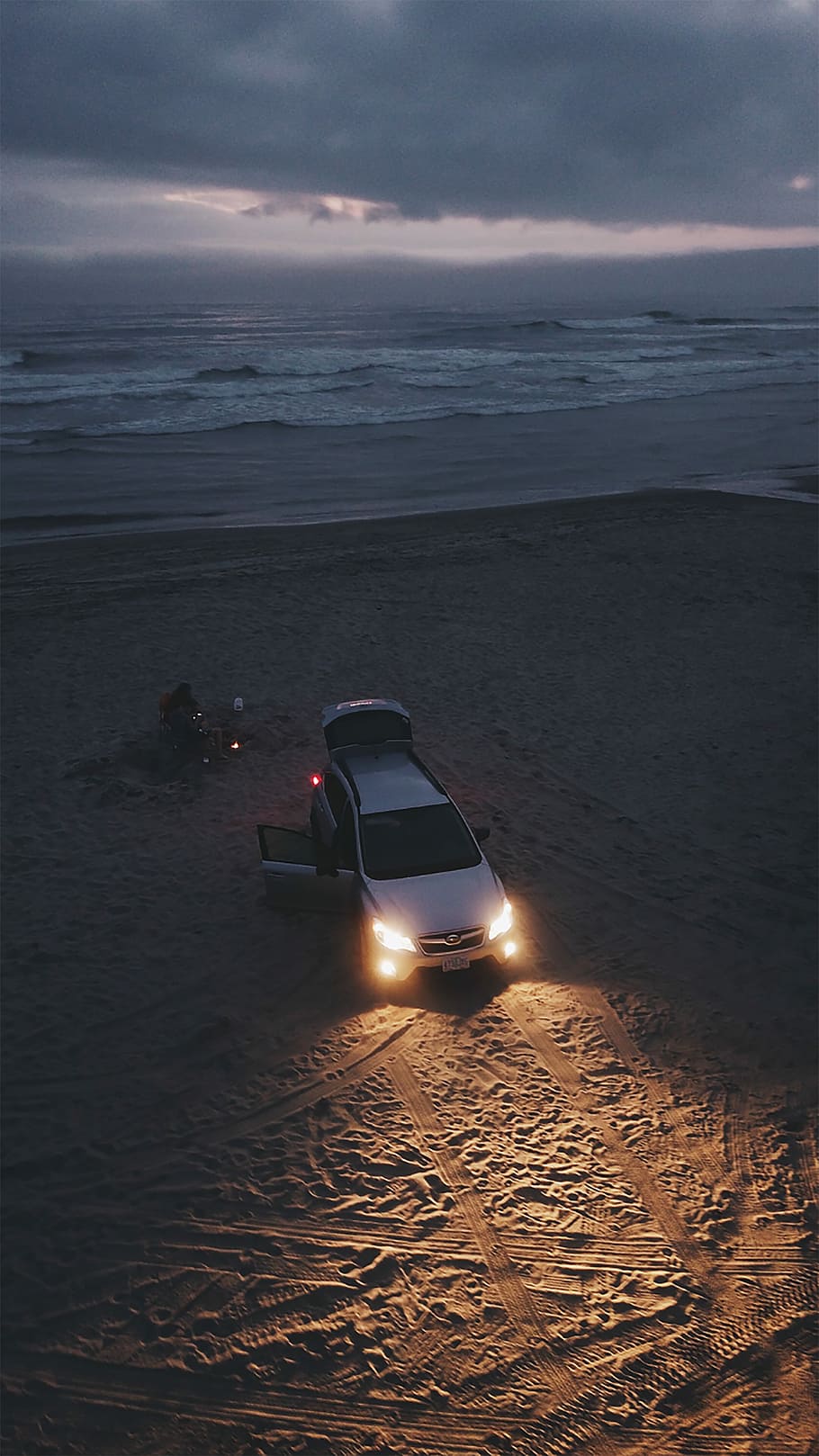 gray vehicle parked near shore line, silver SUV with lighted headlight parked on beach side HD wallpaper