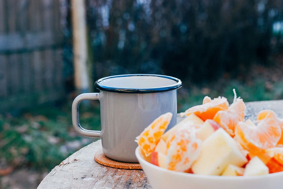 grey mug on brown wooden table, slice orange fruit in white bowl beside grey mug HD wallpaper