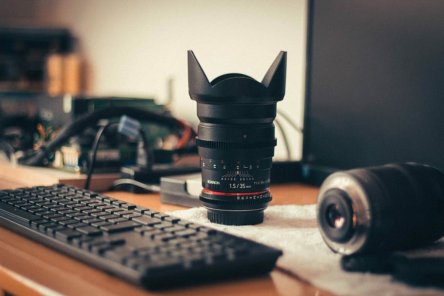 photo zoom lens near keyboard and monitor on tabletop, black telephoto lens beside computer keyboard on table HD wallpaper