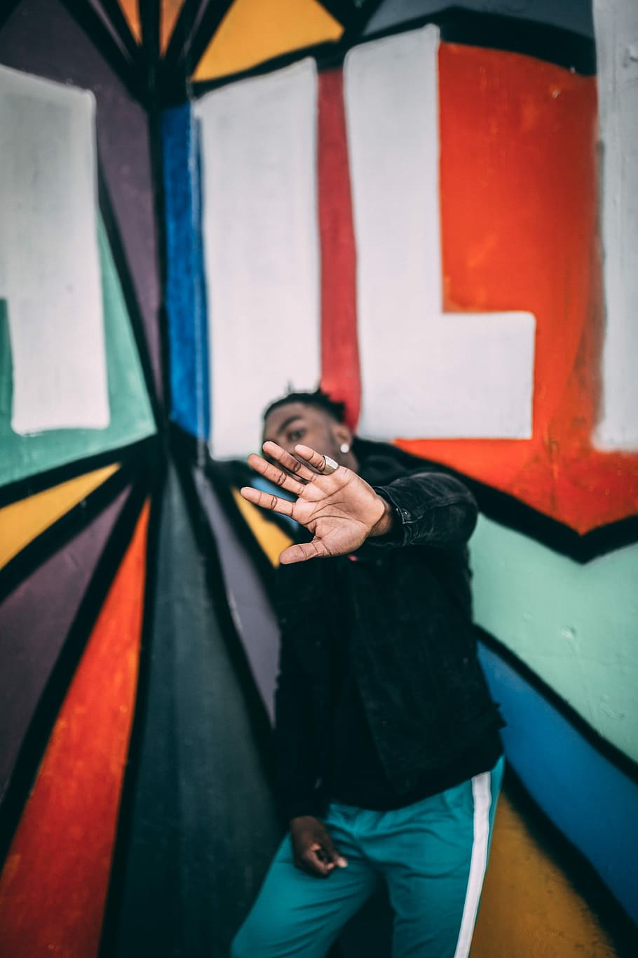 man standing near graffiti wall with arms raised up, tilt-shift photography of man HD wallpaper