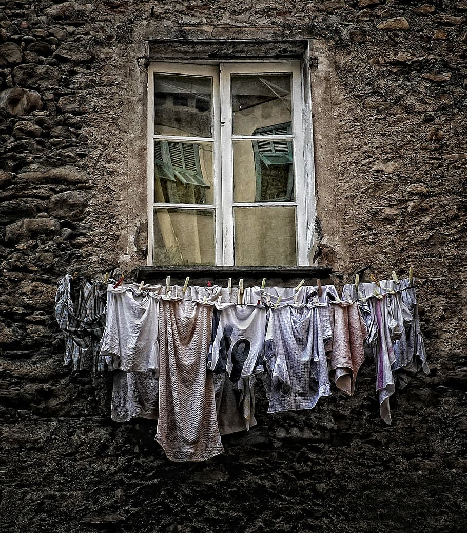 assorted clothes hanged under the window, brown and white apparels near white wooden window