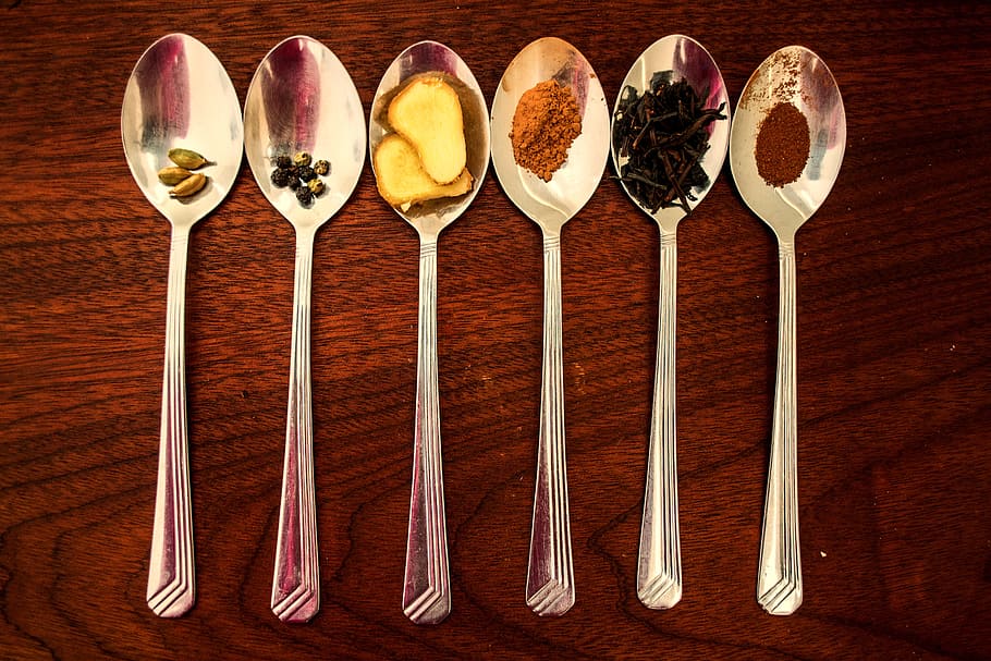 six grey stainless steel spoon with spices, masala, chai, tea